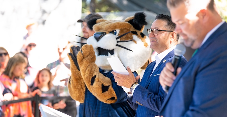 UC Merced mascot Rufus stands and applauds next to Chancellor Juan Sánchez Muñoz at the Applegate Zoo reopening.